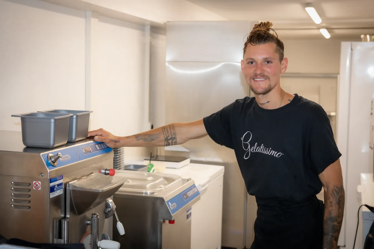 Noah Bühler von Gelatissimo in Egg steht bei seiner Glacémaschine.